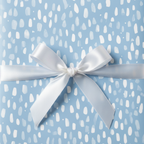Light blue gift wrapped in abstract pattern paper, tied with a white satin bow.
