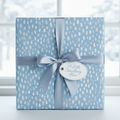 Elegant baby blue wrapping paper with white pattern, tied with a satin ribbon and gift tag.