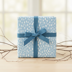 Light blue birthday wrapping paper with abstract raindrop pattern and teal ribbon.