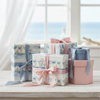 Elegant gifts wrapped in sailboat themed wrapping paper with blush and blue satin ribbons.