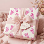Square gift wrapped in baby footprint paper, tied with a pink bow; perfect baby shower wrapping paper.