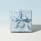 Square gift box wrapped in light blue polka dot wrapping paper with a satin ribbon and matching tag.