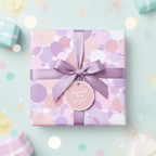 Square gift wrapped in pastel polka dot paper with lavender ribbon and tag.