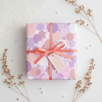 Elegant gift wrapped in pink and lavender polka dot wrapping paper with coral ribbon and gift tag.