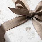 Baptism wrapping paper with elegant vintage sketches and a taupe satin bow by Wrapped Studios.