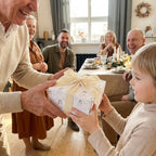 Grandfather giving a gift in elegant baptism wrapping paper with cream bow by Wrapped Studios.