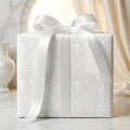 Elegant baptism wrapping paper with crosses and angels, tied with a white satin bow by Wrapped Studios.