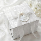 White angel baptism wrapping paper with a sheer ribbon bow on a luxury gift box by Wrapped Studios.