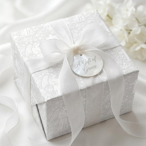 White angel baptism wrapping paper with a sheer ribbon bow on a luxury gift box by Wrapped Studios.