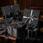 Luxury black floral wrapping paper with elegant satin ribbons and velvet gift boxes by Wrapped Studios.