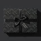 Luxury black gothic floral wrapping paper with a satin bow and gift tag by Wrapped Studios.
