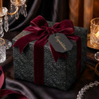 Elegant black floral wrapping paper with a burgundy velvet ribbon on a luxury gift box by Wrapped Studios.