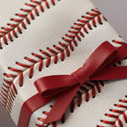 Unique baseball wrapping paper with red stitching detail and tied with a matching red ribbon.
