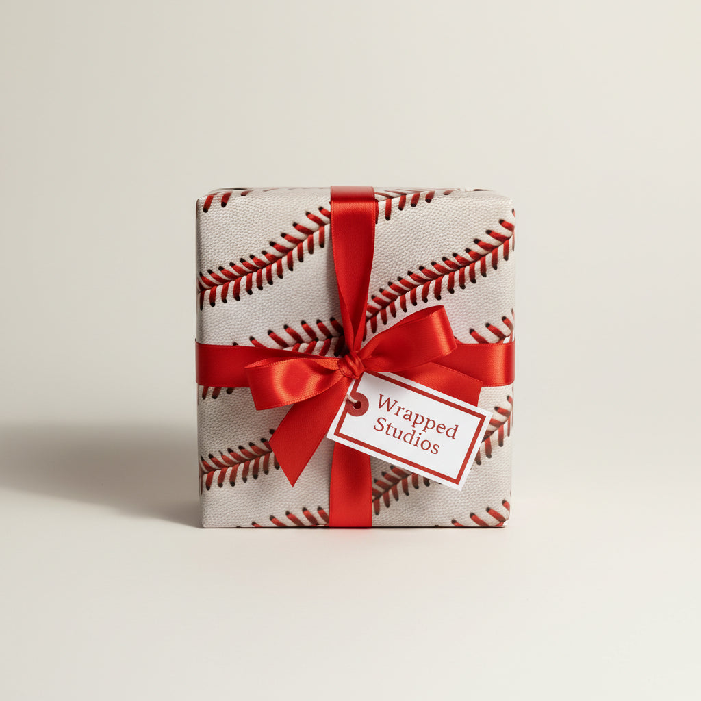 Gift box wrapped in baseball-themed paper, finished with a red satin ribbon and "Wrapped Studios" tag.