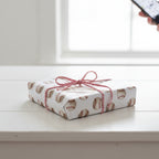 Wrapped Studios baseball wrapping paper. White gift wrap with baseball pattern and red baker's twine.