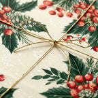 Luxury Christmas wrapping paper with vintage holly and berry pattern, tied with gold string. Wrapped Studios.