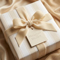 Luxury beige striped wrapping paper with a champagne velvet bow and Wrapped Studios gift tag.