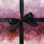 Elegant galaxy wrapping paper in shades of pink and gold with a black satin ribbon.