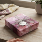 Elegant gift wrapped in pink galaxy wrapping paper with silver ribbon and tag.