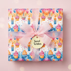 Square gift wrapped in watercolor cupcake birthday wrapping paper with a pink ribbon and "Sweet Wishes" tag.