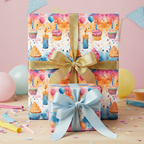 Stacked birthday gifts wrapped in cupcake print paper with gold glitter and blue satin bows.