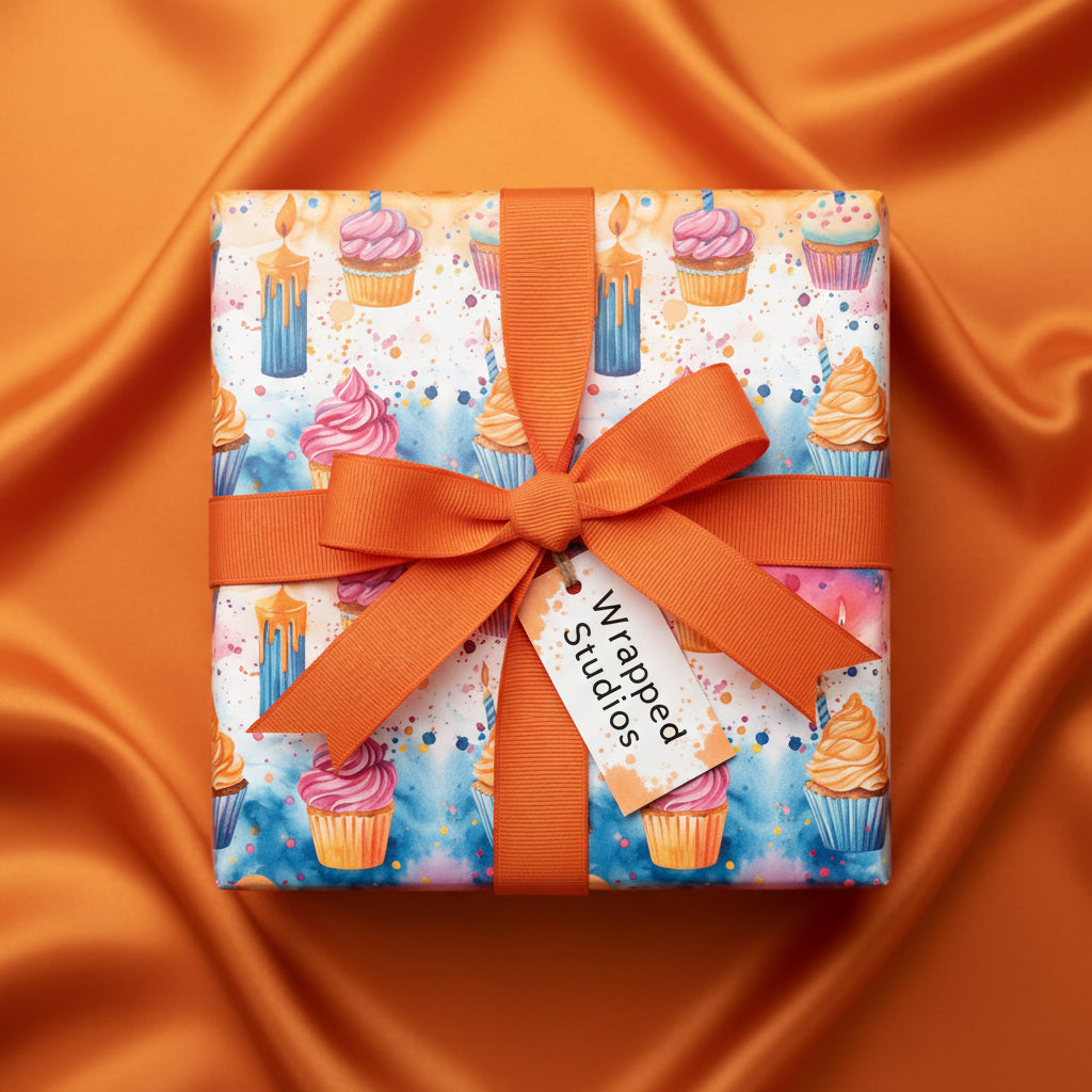 Watercolor cupcake and candle birthday wrapping paper with orange ribbon, on matching orange silk fabric.