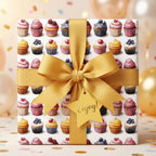 Square gift wrapped in cupcake-patterned birthday wrapping paper with a gold ribbon and a "Enjoy!" gift tag.