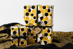Modern polka dot wrapping paper in yellow, black, and gold for luxury gifts, tied with a black ribbon and "Me & You" tag.