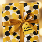 Modern polka dot wrapping paper in black, white, and gold with a satin gold ribbon and "A Little Sparkle" gift tag.