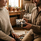Man giving a gift wrapped in dark floral wrapping paper with a cream bow by Wrapped Studios.