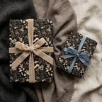 Moody dark floral wrapping paper with velvet and satin bows on gift boxes by Wrapped Studios.