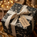 Moody dark floral wrapping paper with a rustic linen ribbon and gift tag by Wrapped Studios.