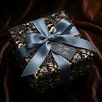 Luxury dark floral wrapping paper with a blue satin bow on a gift box, by Wrapped Studios.
