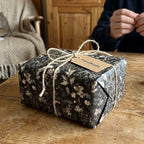 Vintage dark floral wrapping paper by Wrapped Studios on a gift box tied with rustic twine.