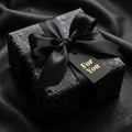 Black luxury gift wrap with satin ribbon and "For You" tag, presented by Wrapped Studios.