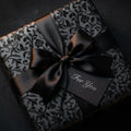 Elegant floral gift wrap in black with a satin bow.