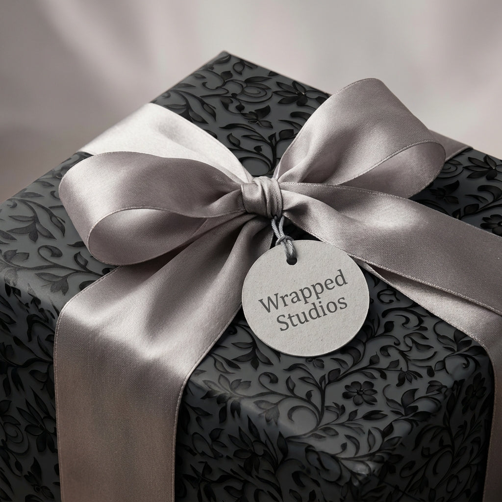 Elegant Wrapped Studios gift with black floral wrapping paper and a satin silver bow.