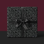 Elegant black floral wrapping paper with satin ribbon from Wrapped Studios.