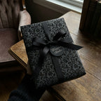 Wrapped Studios black floral wrapping paper with black ribbon, elegant gift wrap.