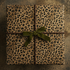Square gift box wrapped in leopard print paper with green velvet ribbon.