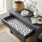 Black and white dog paw print wrapping paper lining a gray drawer, by Wrapped Studios.