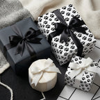 Black and white paw print wrapping paper on gift boxes with satin bows by Wrapped Studios.