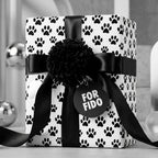 Dog paw print wrapping paper by Wrapped Studios on a gift with a black satin bow and "For Fido" tag.