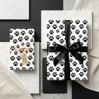 Dog paw print wrapping paper in black and white with a black satin ribbon by Wrapped Studios.