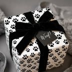 Dog paw print wrapping paper with a black velvet ribbon and Woof tag by Wrapped Studios.