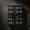 Monochrome tire tread wrapping paper on a gift box tied with a black satin ribbon bow.