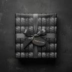 Monochrome gift wrap featuring a car tire tread pattern, tied with a satin ribbon and tag that reads "Built to Last".