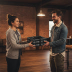 Man gives woman a gift wrapped in black tire tread patterned wrapping paper with a black ribbon.