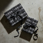 Two tire tread pattern gifts wrapped with striped black ribbon, unique gift wrap for car enthusiasts.