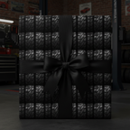 Unique automotive gift wrap: square gift box in tire tread patterned paper with elegant black ribbon bow, garage setting.